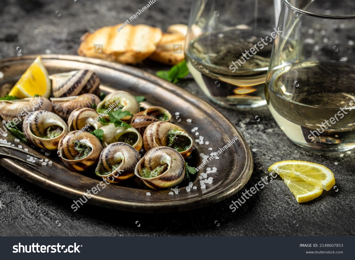 Baked snails with butter and spice on dark background. Snails baked with sauce, Bourgogne Escargot Snails. gourmet food. concept of french cuisine, Long banner format. top view. #2148607853