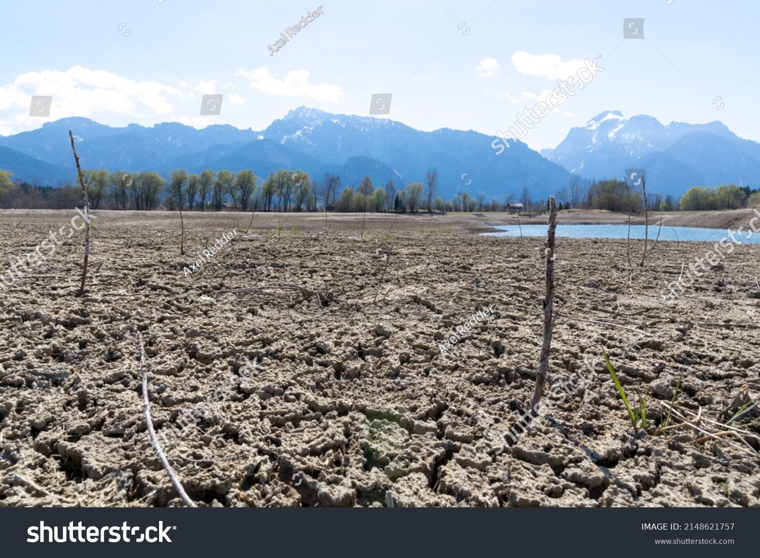 environmental protection, drought in germany and europe, a dried up lake in the alps, in the background mountains and houses #2148621757