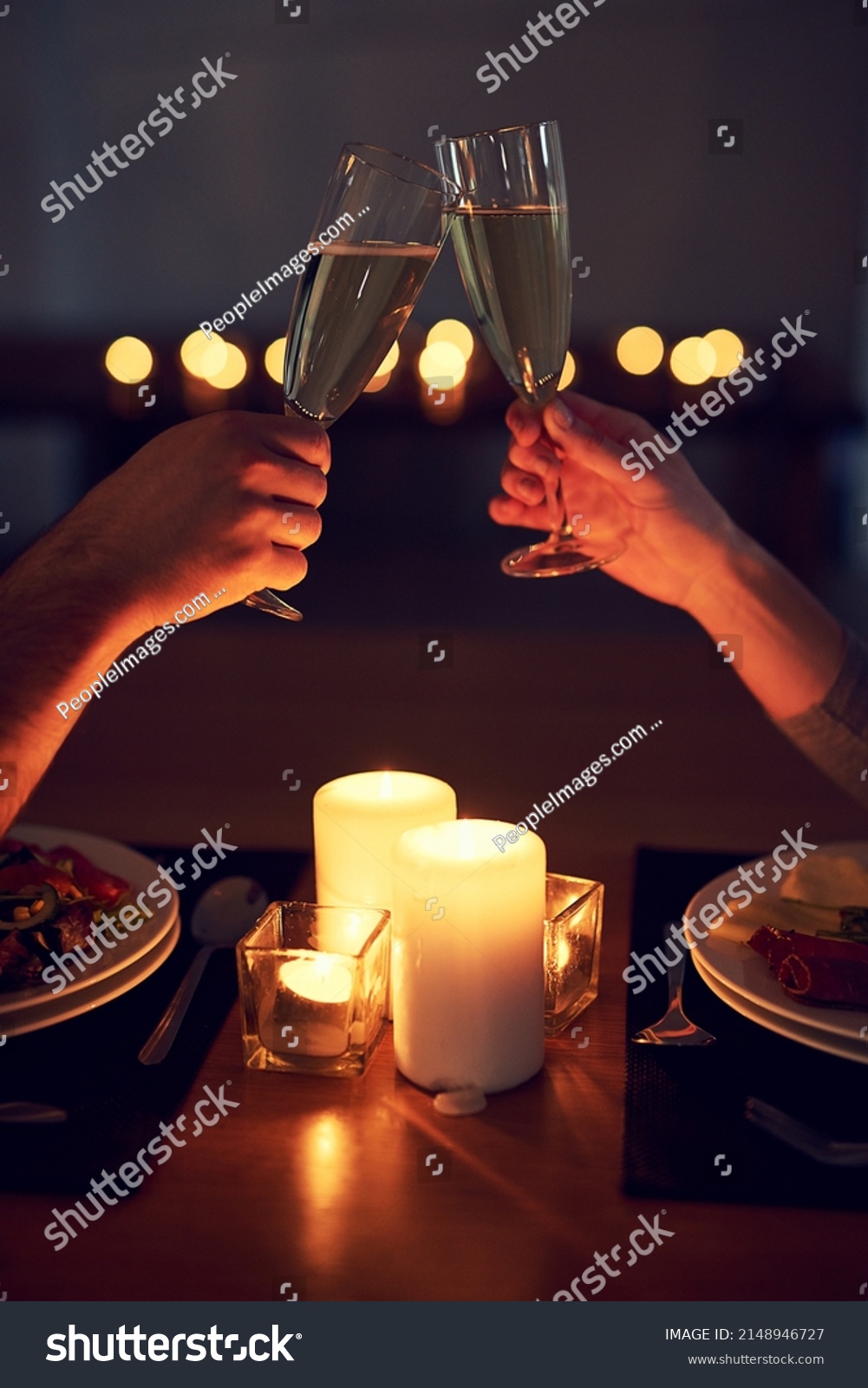 Heres to us and our future. Cropped shot of an unrecognizable couple having a celebratory toast over a candle lit dinner at night. #2148946727