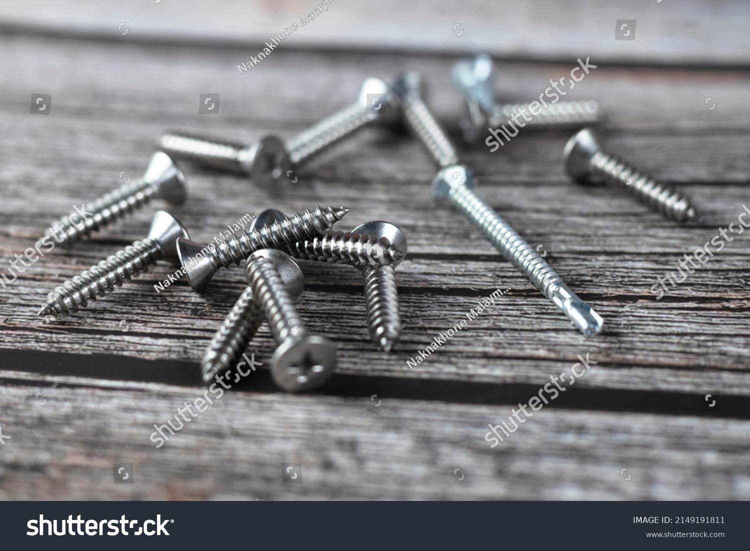 Tapping screws made of steel on wood background, metal screw, iron screw, chrome screw, screws as a background, wood screw, concept industry. copy space for text. #2149191811