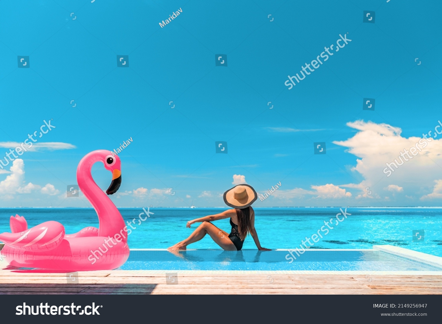 Travel on beach by pool on summer vacation in luxury resort. Woman relaxing in bikini by inflatable pink flamingo toy pool float on ocean turquoise background. Holiday travel destination concept. #2149256947