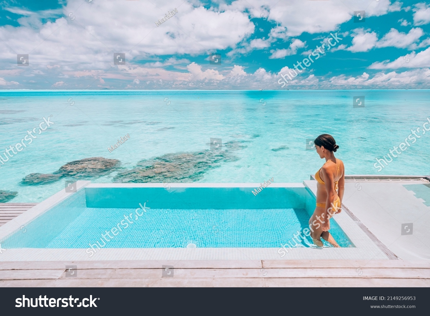 Luxury resort travel vacation destination idyllic overwater bungalow villa woman relaxing by infinity pool. Social media influencer traveler luxurious high end lifestyle. #2149256953