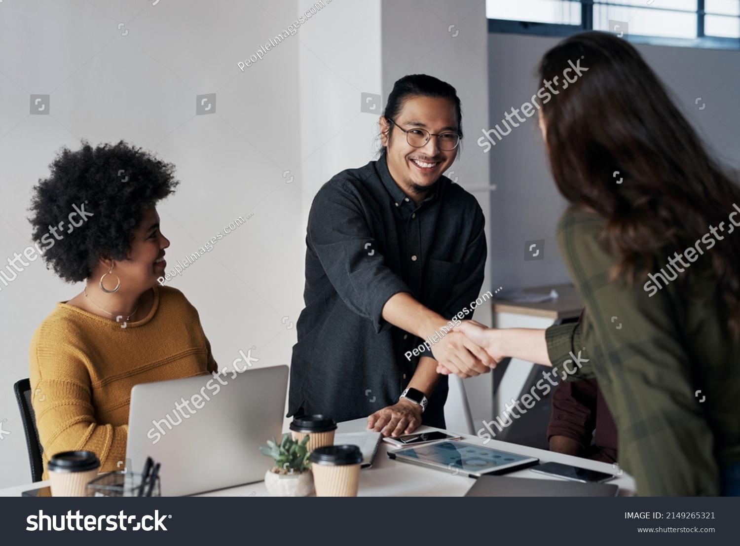 Its been a pleasure doing business with you. Cropped shot of a group of young businesspeople greeting each other with a handshake before sitting down in the office. #2149265321