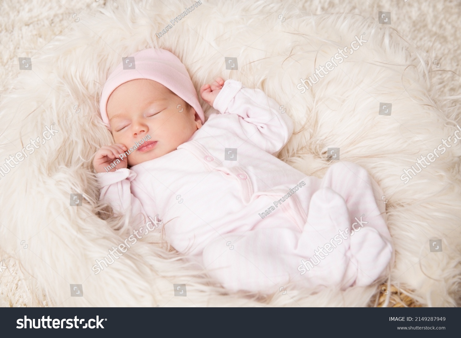 Newborn Baby Girl sleeping over Fluffy White Blanket. Adorable One Month Child in Pink Bodysuit dreaming over Beige Furry Carpet. Cute New Born Kid relax #2149287949