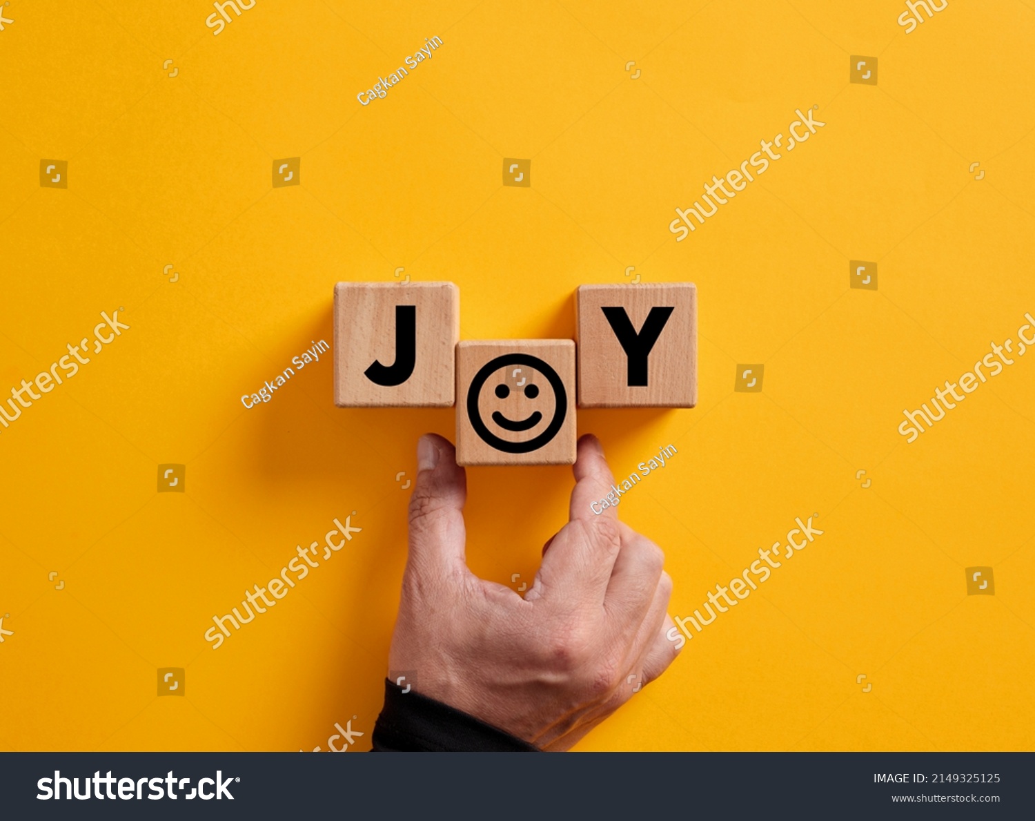 Hand places the word joy on wooden blocks with a smiling face symbol. Joy, happiness, pleasure, joyful emotion. #2149325125
