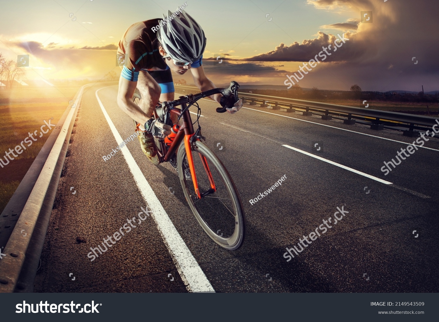 The cyclist rides on his bike at sunset. Dramatic background. #2149543509