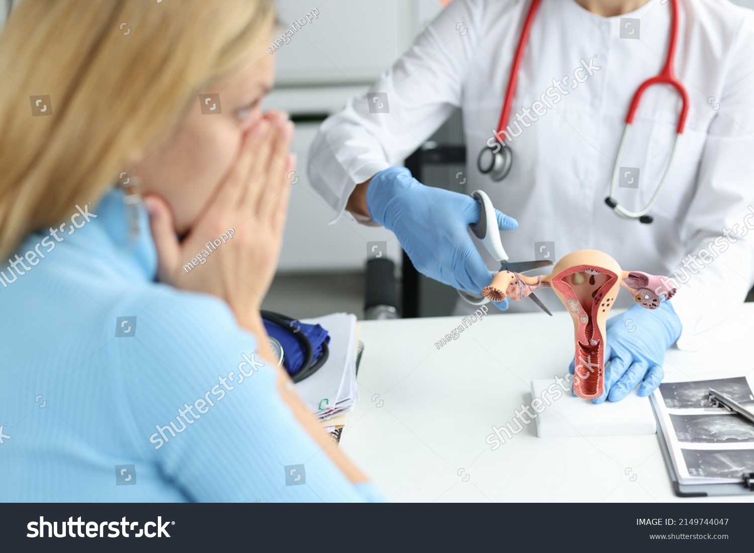Doctor climbing fallopian tube with scissors onto artificial models on uterus and ovaries in clinic. Infertility obstruction of fallopian tubes concept #2149744047