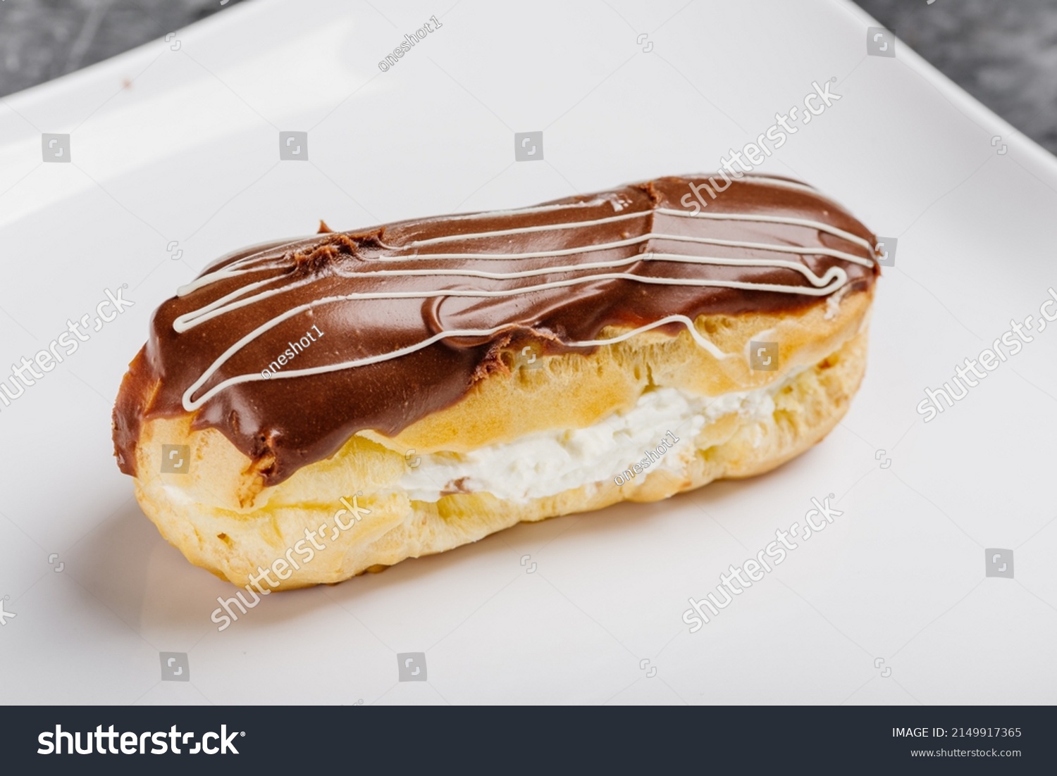 Eclair with chocolate on a white plate. Traditional french eclairs with chocolate. Tasty colorful dessert profiteroles. chocolate eclair, Traditional french dessert eclair with custard and chocolate.  #2149917365