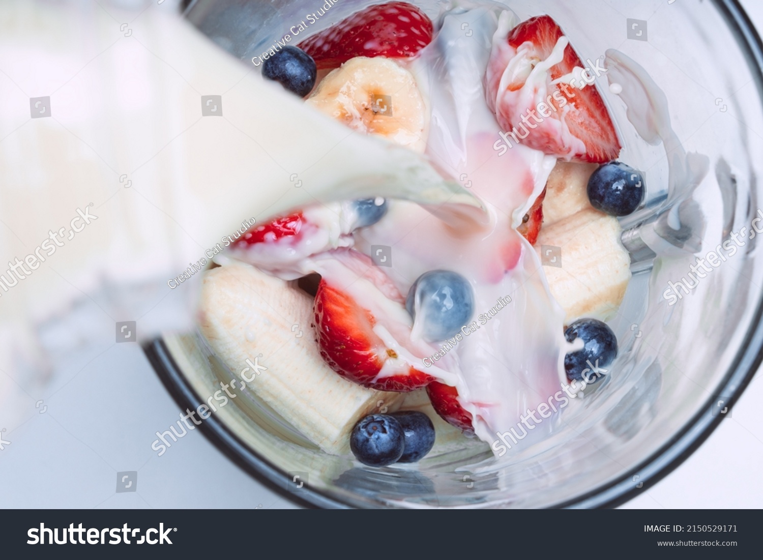 Making smoothie or milkshake in blender. Pouring milk in a blender with fruits. Vegan smoothie with almond milk #2150529171