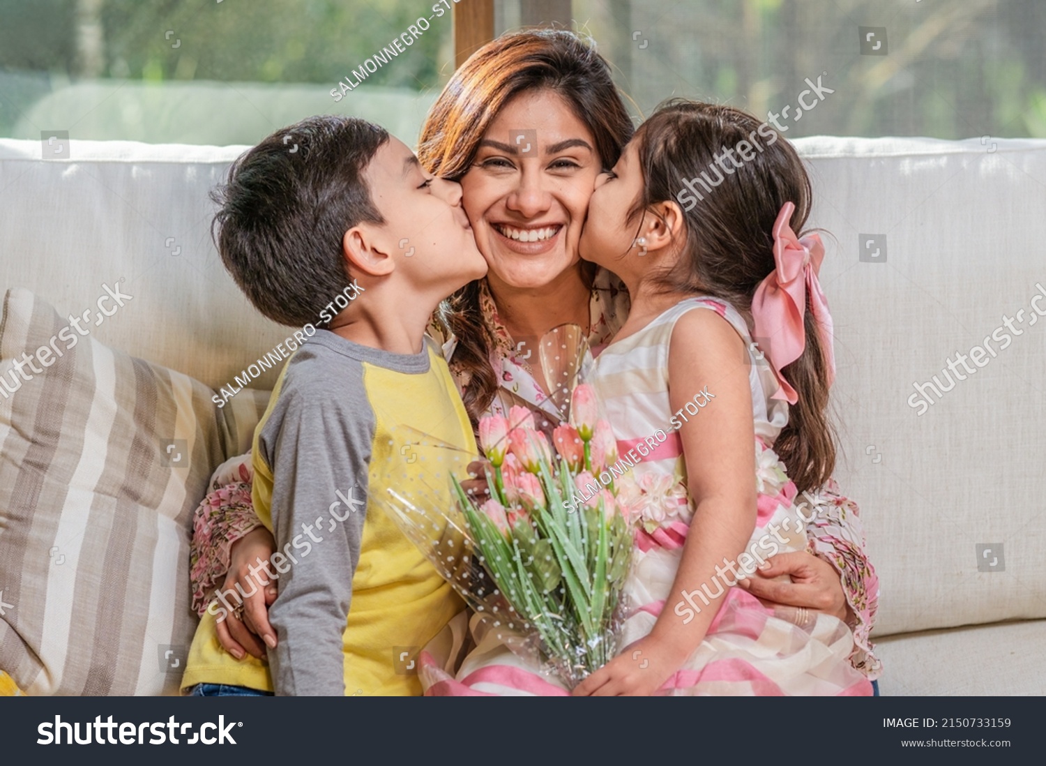 Mother's Day.  Latin mother holds her two children, a boy, and a girl, as they hug and kiss her. #2150733159