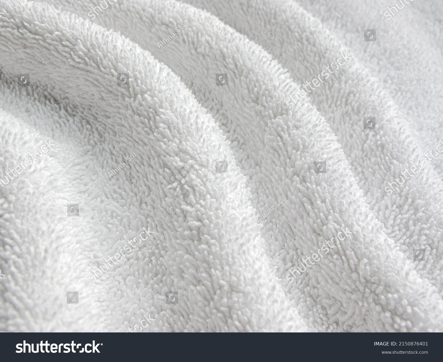 White background of towel texture. White towel lies in twisted beautiful folds. Macro photo of terry cloth or beach towel. Soft textile background. #2150876401