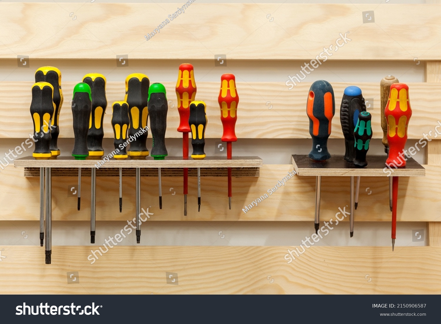 Screwdrivers in workshop. Set of Screw Drivers. Multicolored screwdrivers hanged on shelf.  #2150906587
