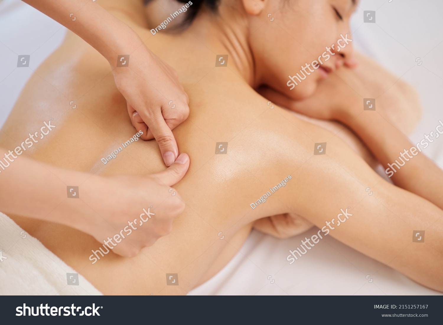 Masseur giving deep tissue back massage to young female client #2151257167