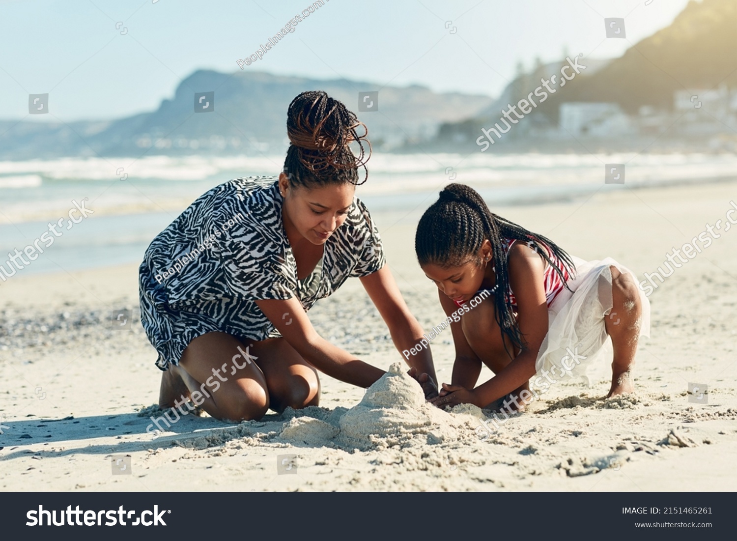 Its their favourite beach activity. Shot of a mother and her little daughter building a sandcastle together at the beach. #2151465261