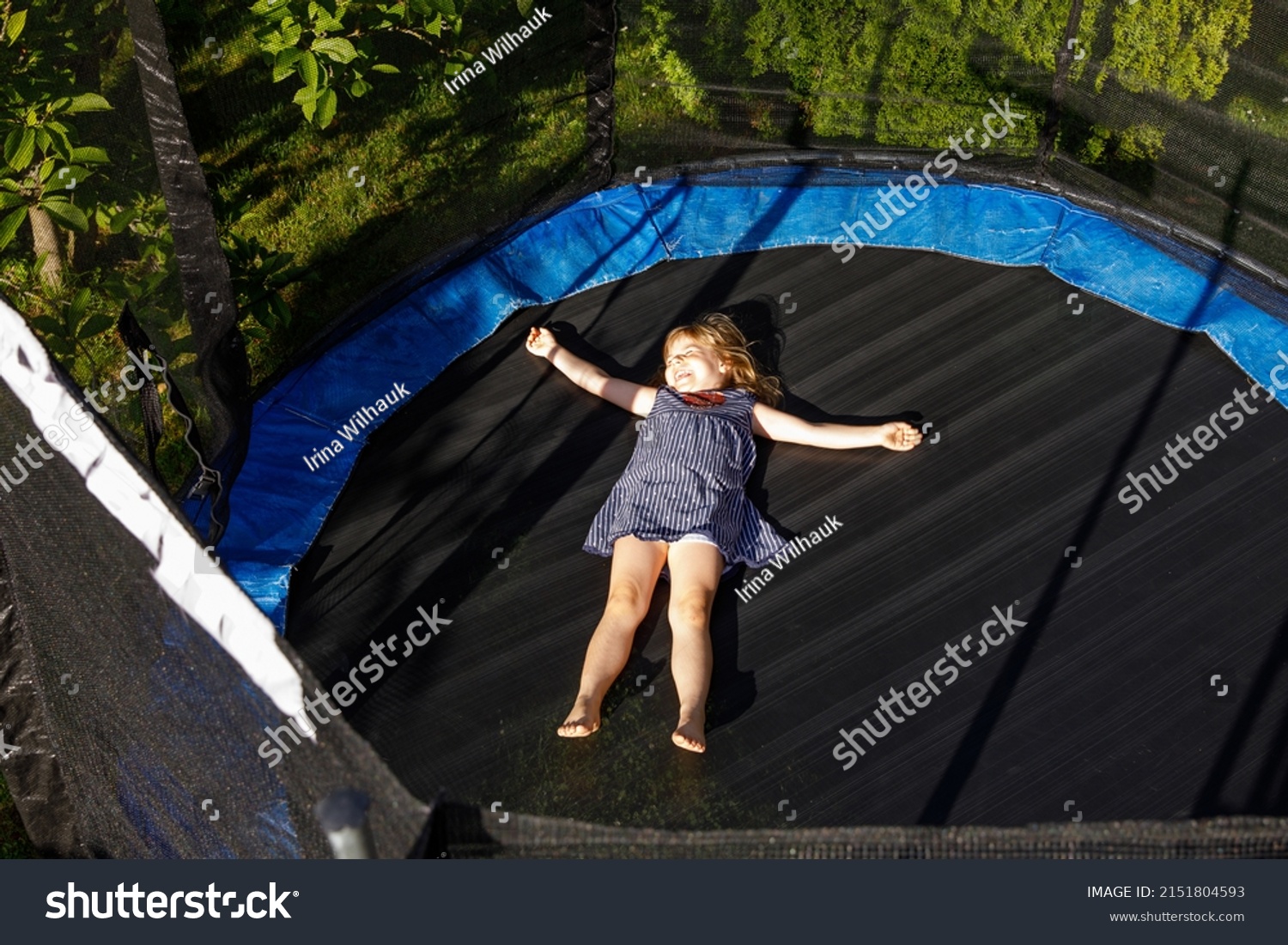 Little preschool girl jumping on trampoline. Happy funny toddler child having fun with outdor activity in summer. Sports and exercises for children. #2151804593