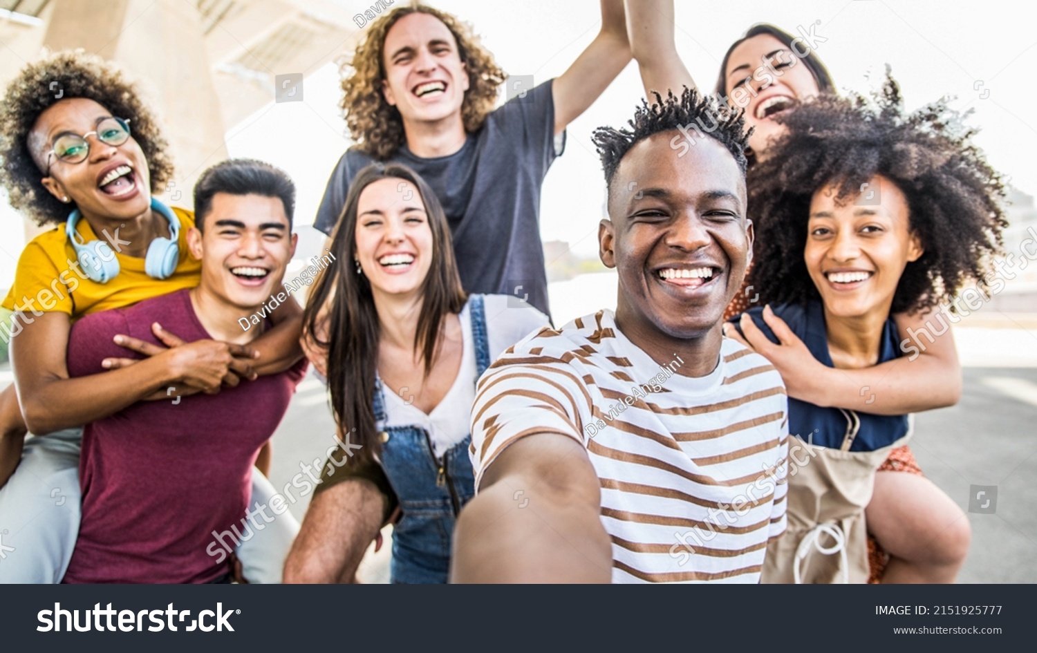 Group multiracial friends taking selfie picture with mobile smartphone outside - Happy young with hands up laughing at camera - Youth concept with guys and girls having fun walking on city street #2151925777