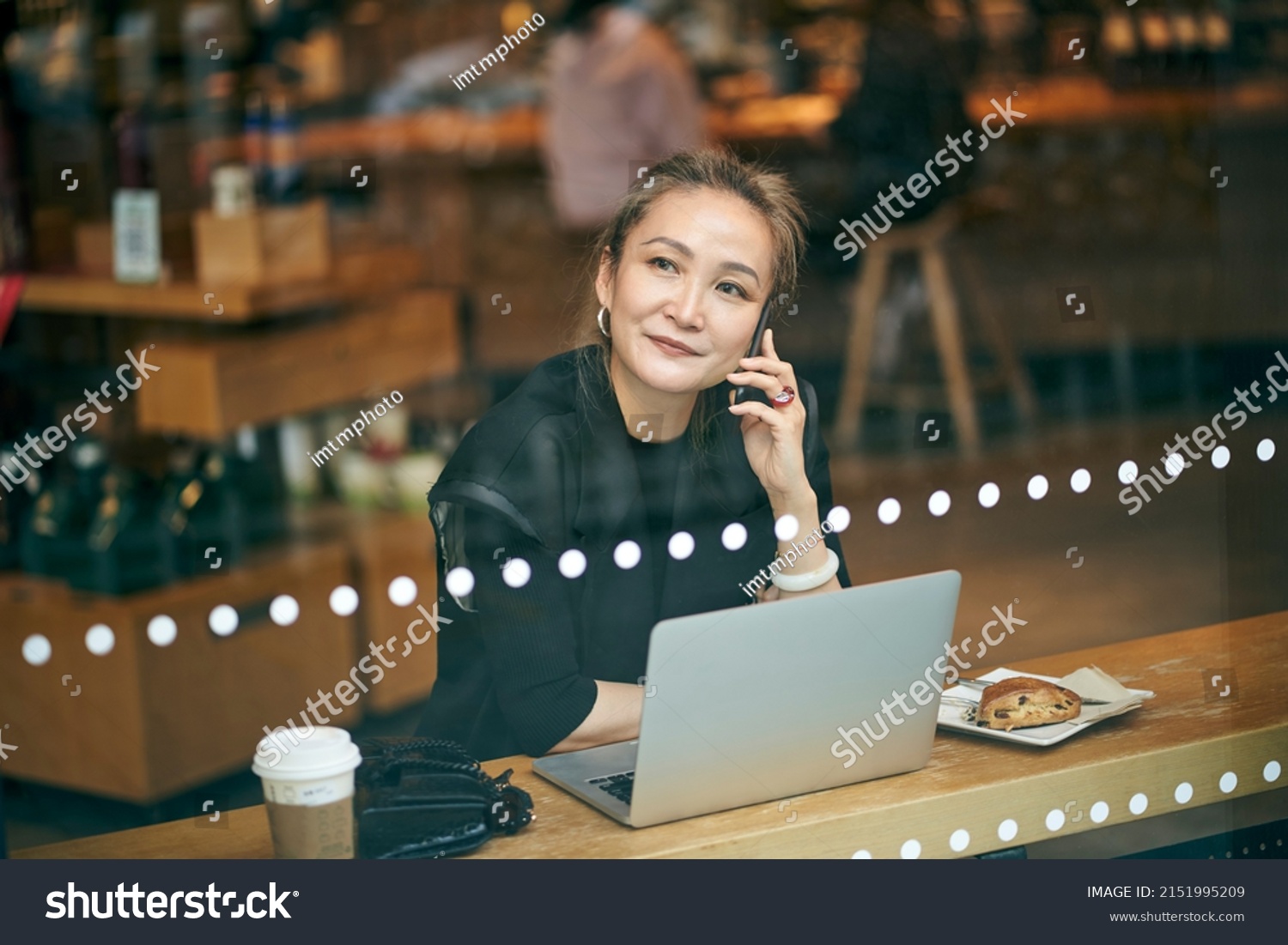 mature asian business woman working in coffee shop using cellphone and laptop computer #2151995209