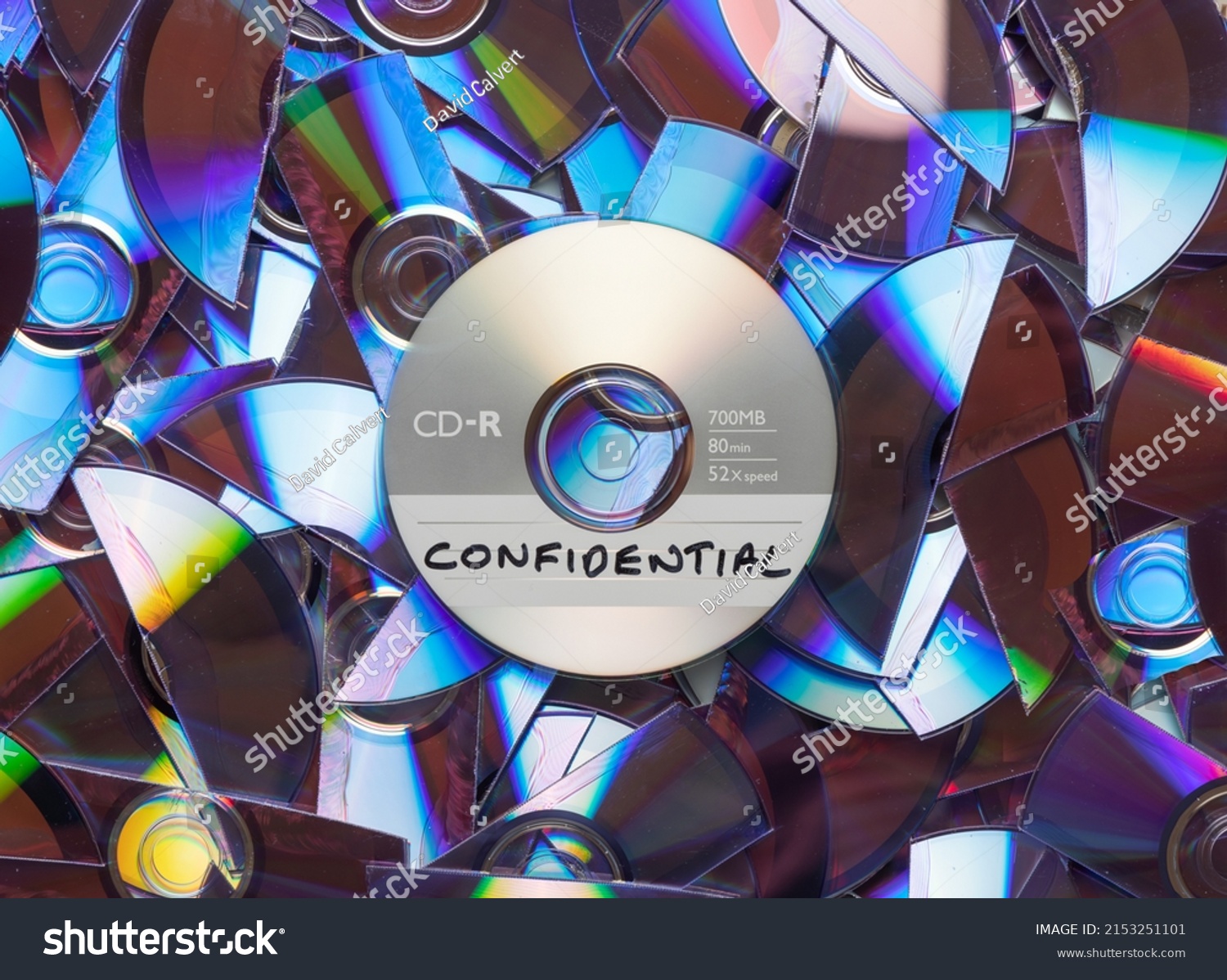 CD with confidential written on it, with shredded CD's and DVD's in the background. #2153251101