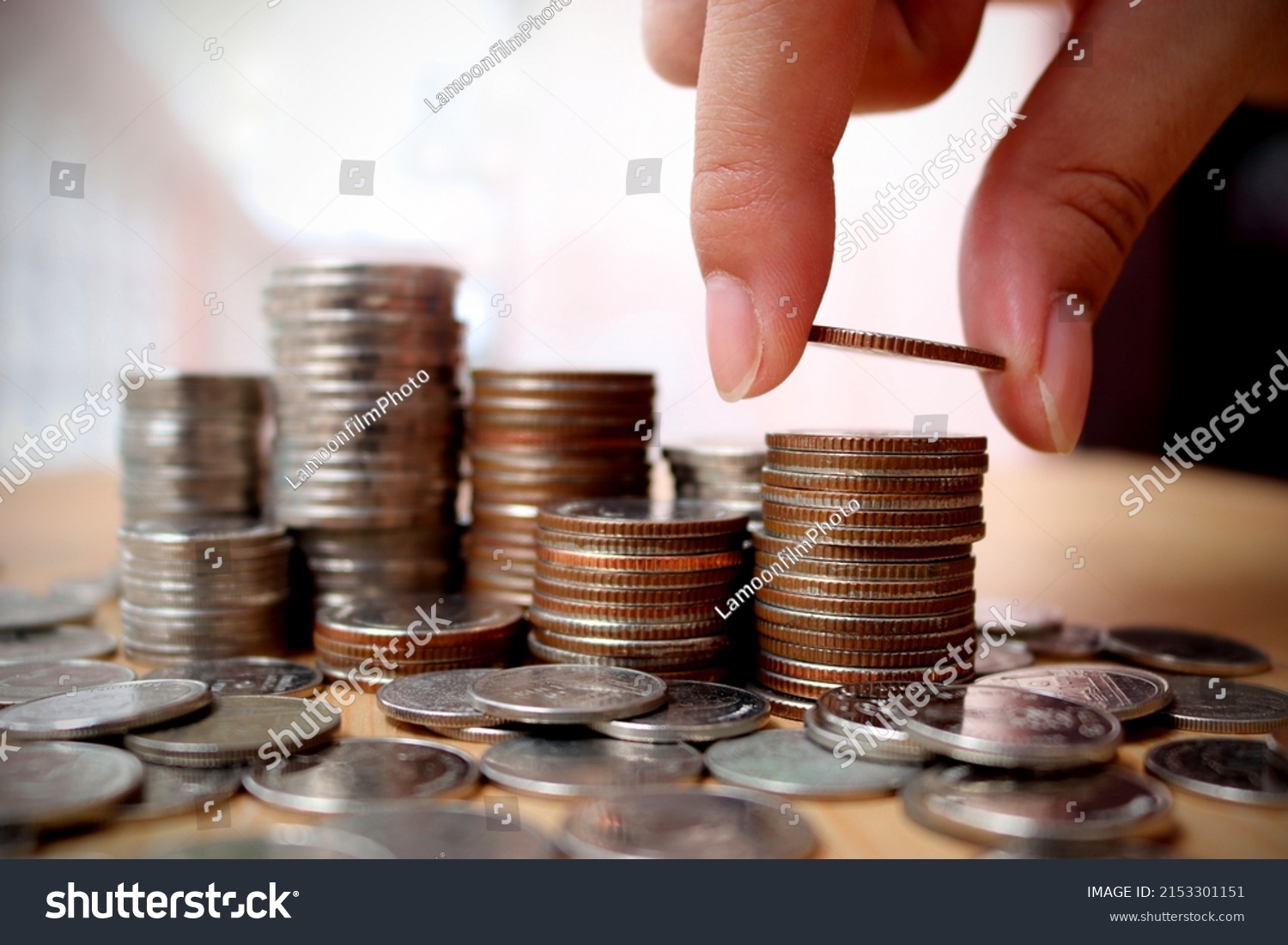Close up of hand putting coins increase arranged on table. To convey the concepts of finance and Retirement fund. #2153301151