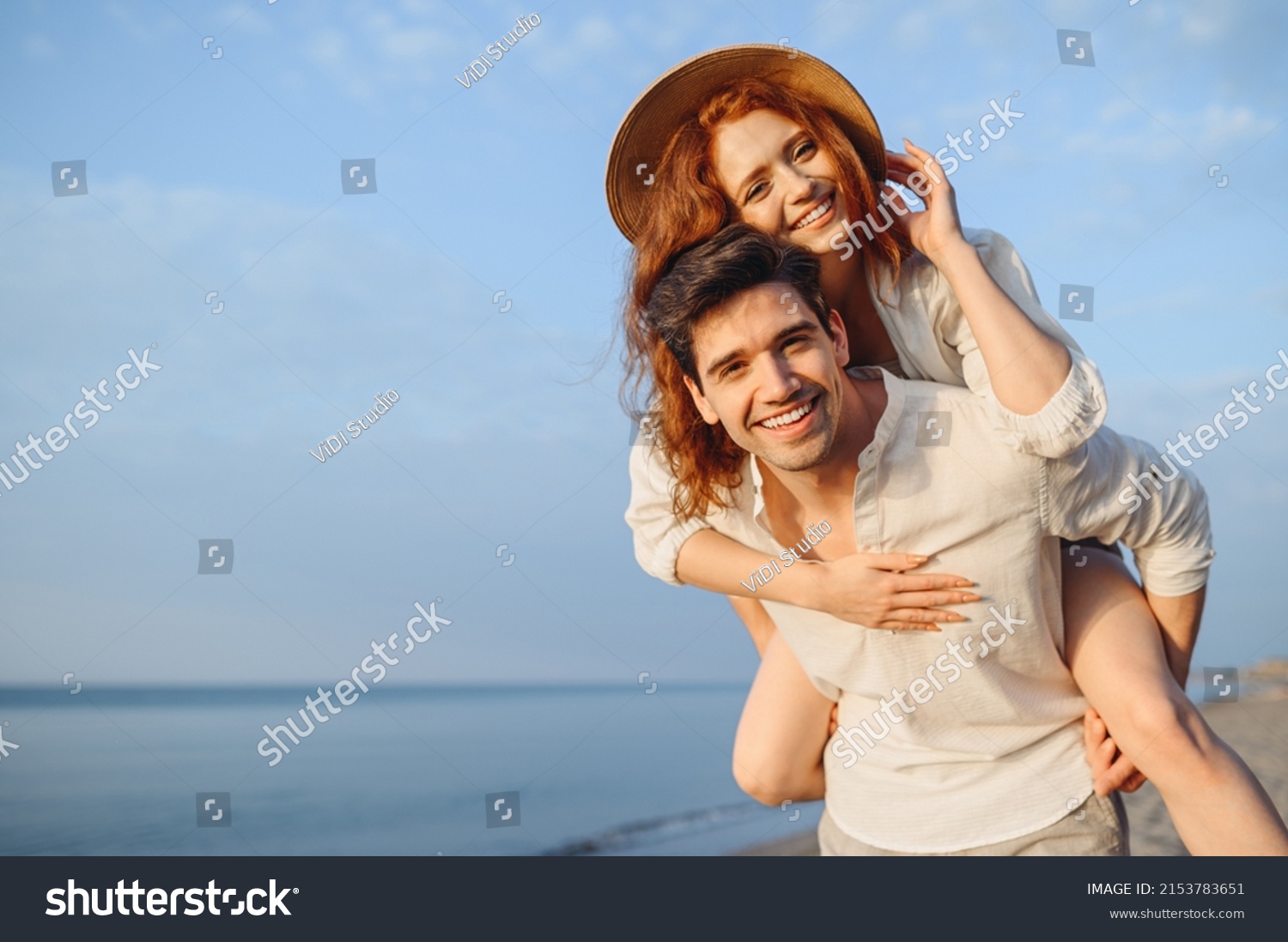Young cheerful happy couple two friends family man woman in white clothes boyfriend give piggyback ride to joyful, girlfriend sit on back at sunrise over sea beach ocean outdoor seaside in summer day #2153783651