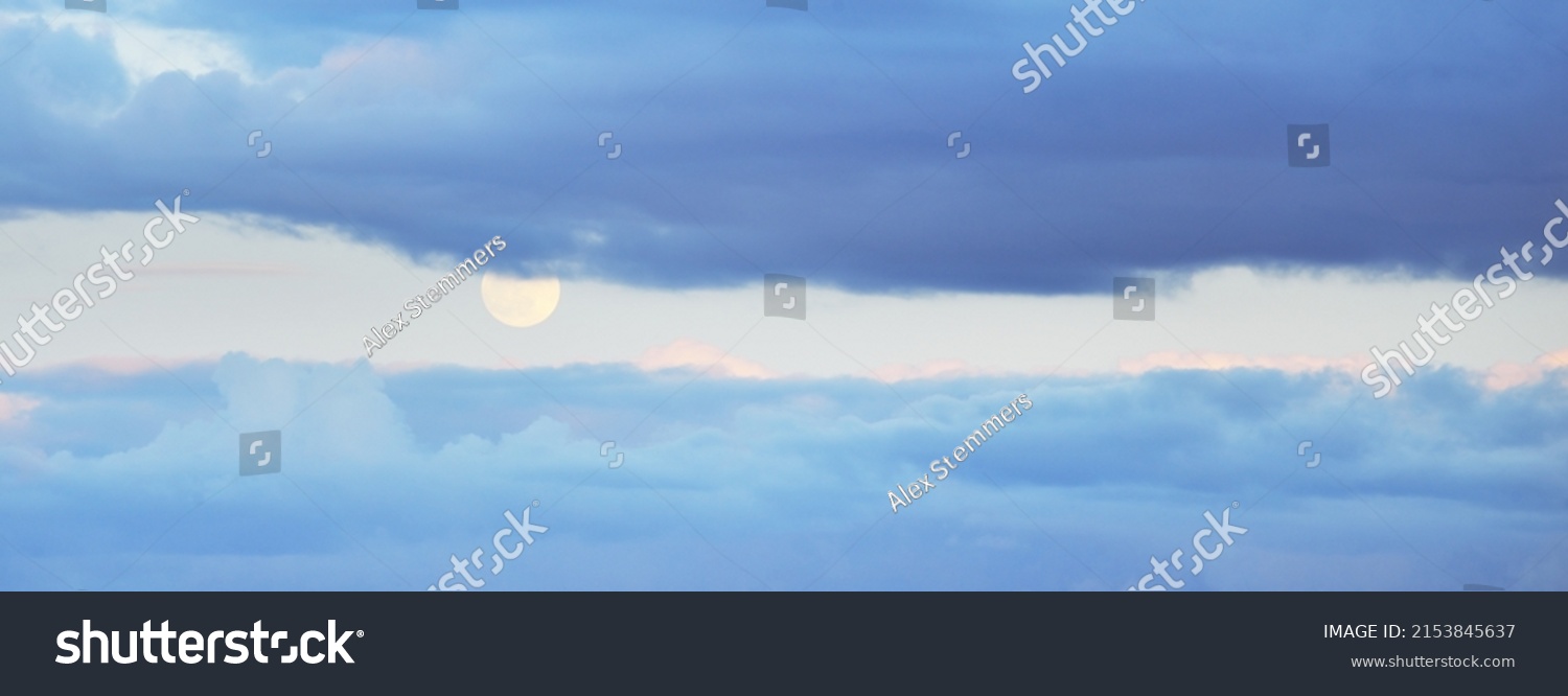Full moon in a clear blue sky with colorful pink sunset cumulus clouds. Dramatic cloudscape. Natural phenomenon, meteorology, hope, heaven, peace, mystery, moonlight, twilight. Panoramic image #2153845637