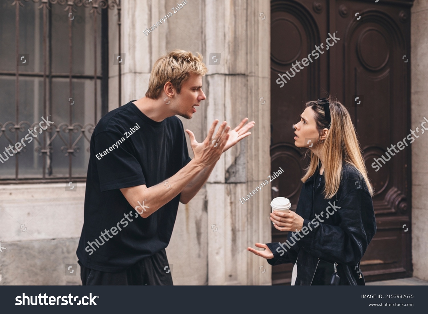 Young arguing sad couple two friends family man woman in casual clothes screaming scolding together walking outdoor near door of home. Man yelling at woman. Couple arguing, having relationship problem #2153982675