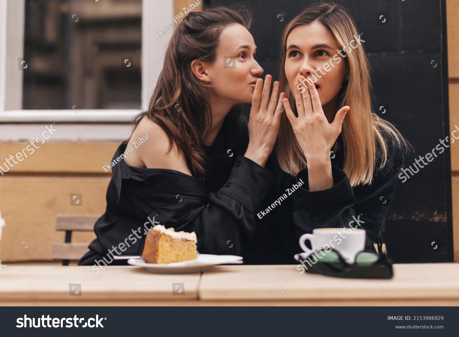 Gossiping. Two beautiful young women gossiping telling something on ear while sitting in the cafe. Communication and friendship concept. Young woman telling her friend some secrets. #2153986929