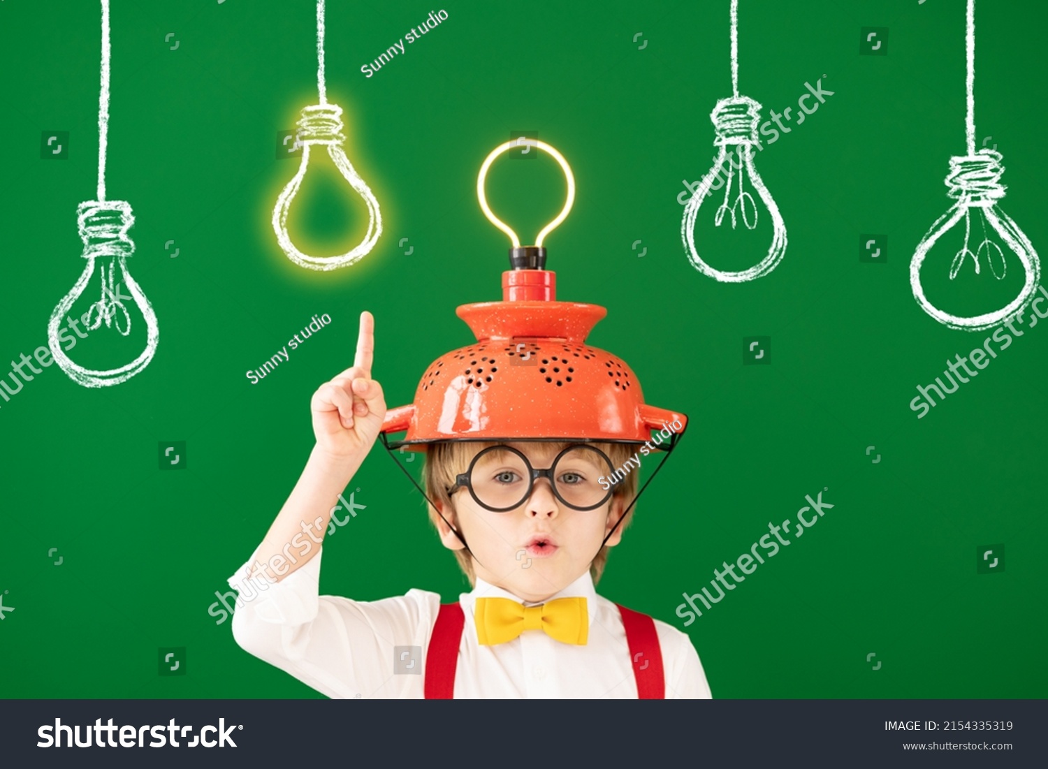 Smart child in the class against blackboard. Funny kid with lightbulb at school. Education, start up and business idea concept #2154335319