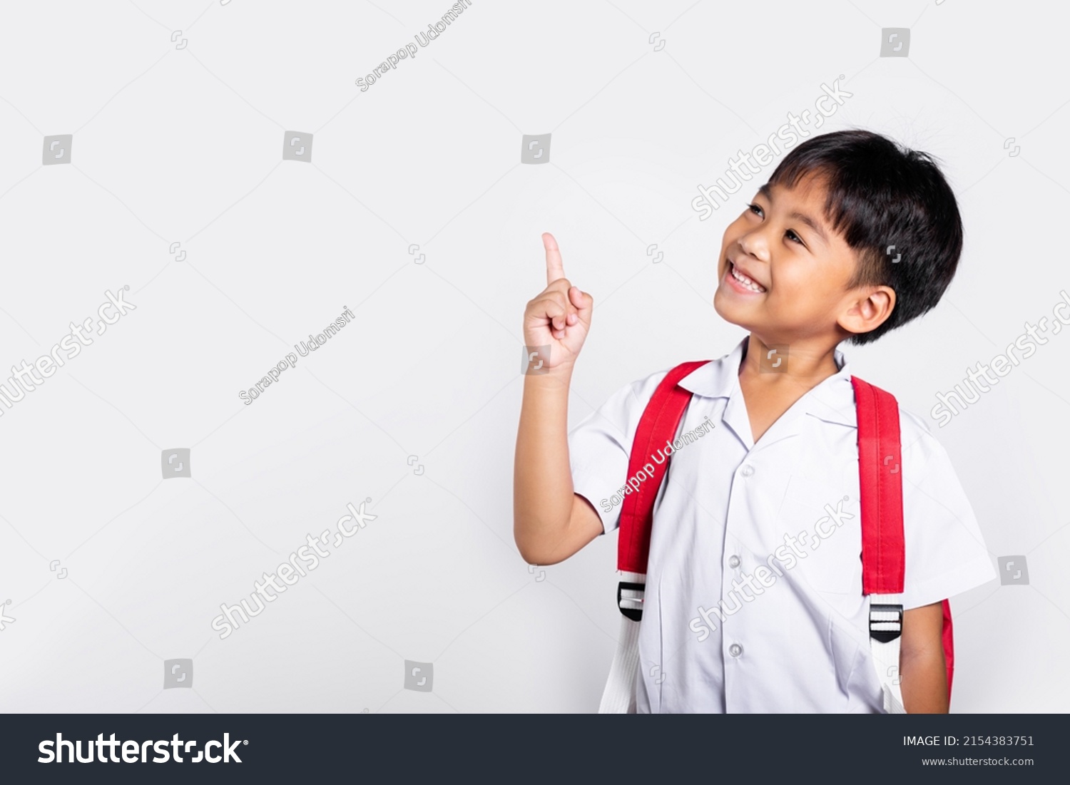 Asian toddler smiling happy wear student thai uniform red pants keeps pointing finger at copy space in studio shot isolated on white background, Portrait little children boy preschool, Back to school #2154383751