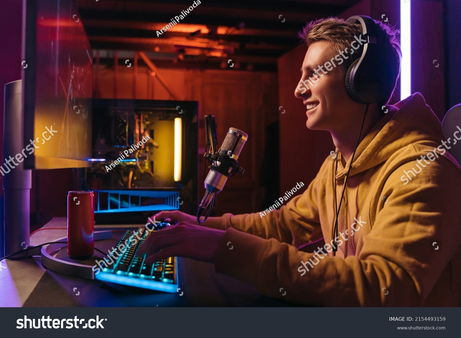  Excited caucasian gamer streamer with headphones playing computer pc video at his living room, recording live stream using microphone, drinking energy drink. Cyber sport and social media concept #2154493159