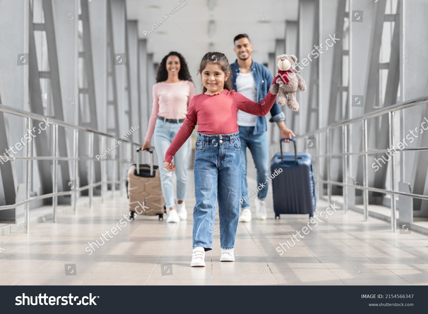 Portrait Of Joyful Cute Middle Eastern Girl Walking At Airport With Parents, Happy Young Arabic Family Ready For Vacation Trip Together, Going To Departure Gate At Terminal, Selective Focus On Kid #2154566347