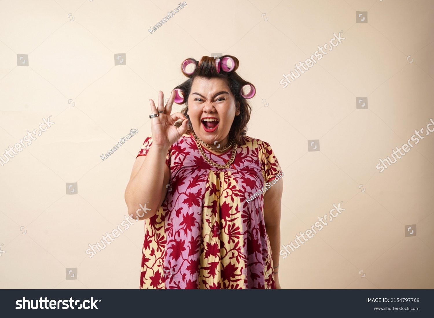 An Asian woman gesturing okay sign using her hand. Isolated on cream background.  #2154797769