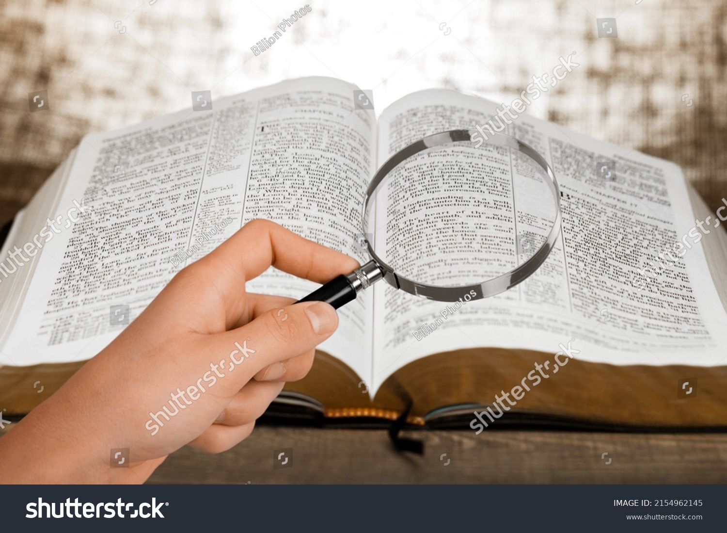 A magnifying glass in hand with open bible book. #2154962145