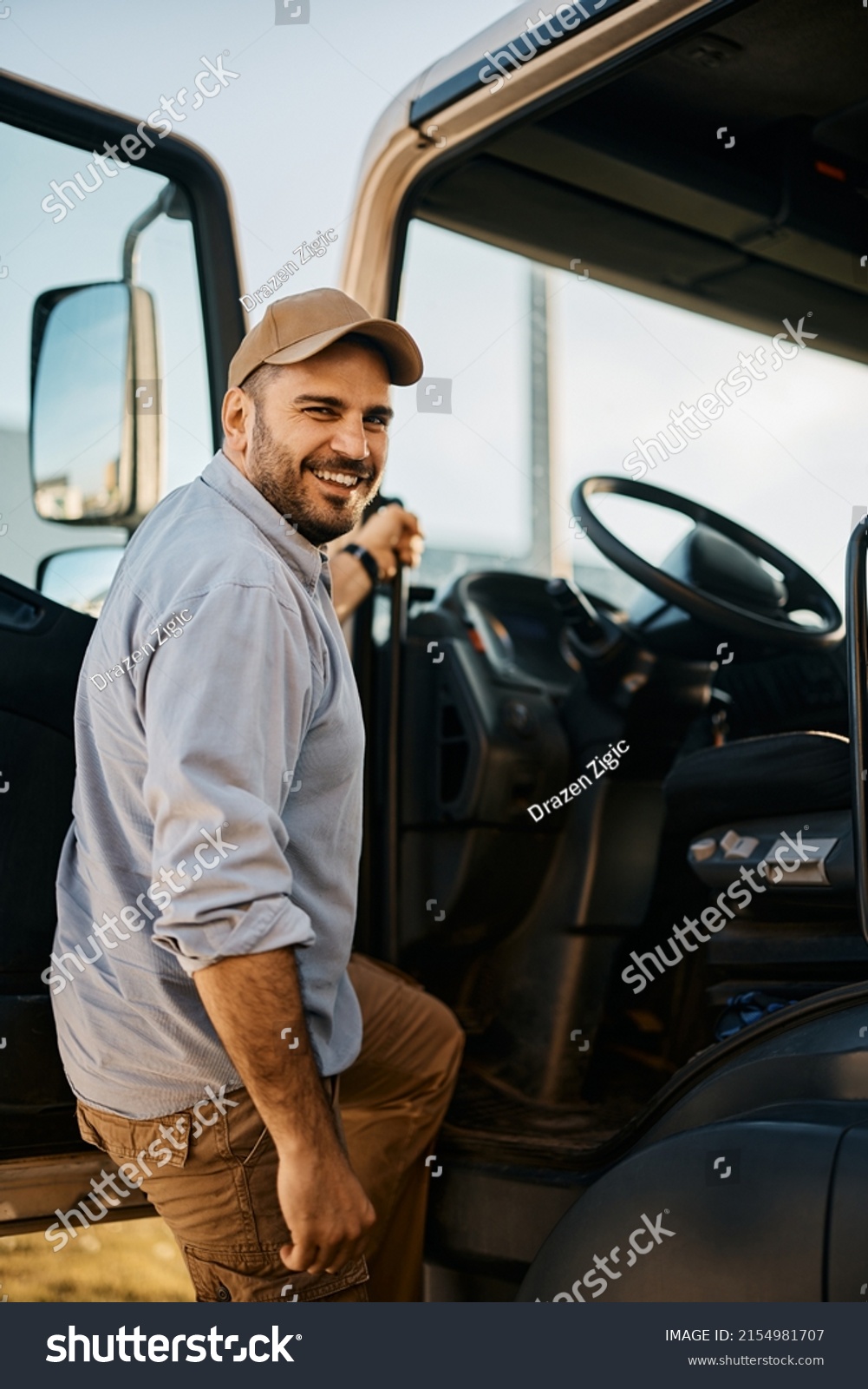 Happy truck driver entering in vehicle cabin and looking at camera.                                                          #2154981707