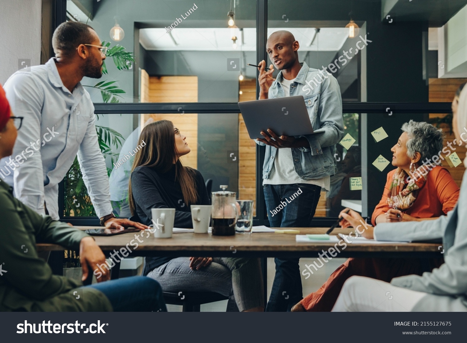 Diverse business professionals having a discussion during a meeting in a modern office. Team of multicultural businesspeople sharing creative ideas in an inclusive workplace. #2155127675