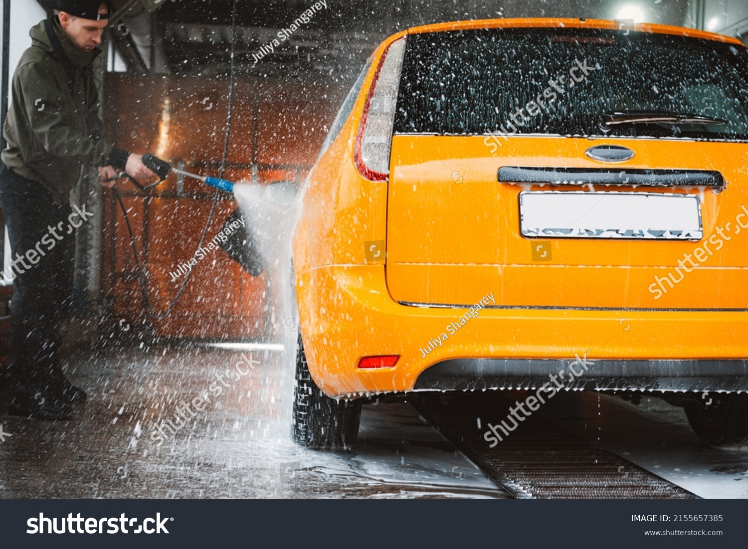 Washing a yellow car at a contactless self-service car wash. Washing a sedan car with foam and high-pressure water. Spring cleaning at the car wash. #2155657385