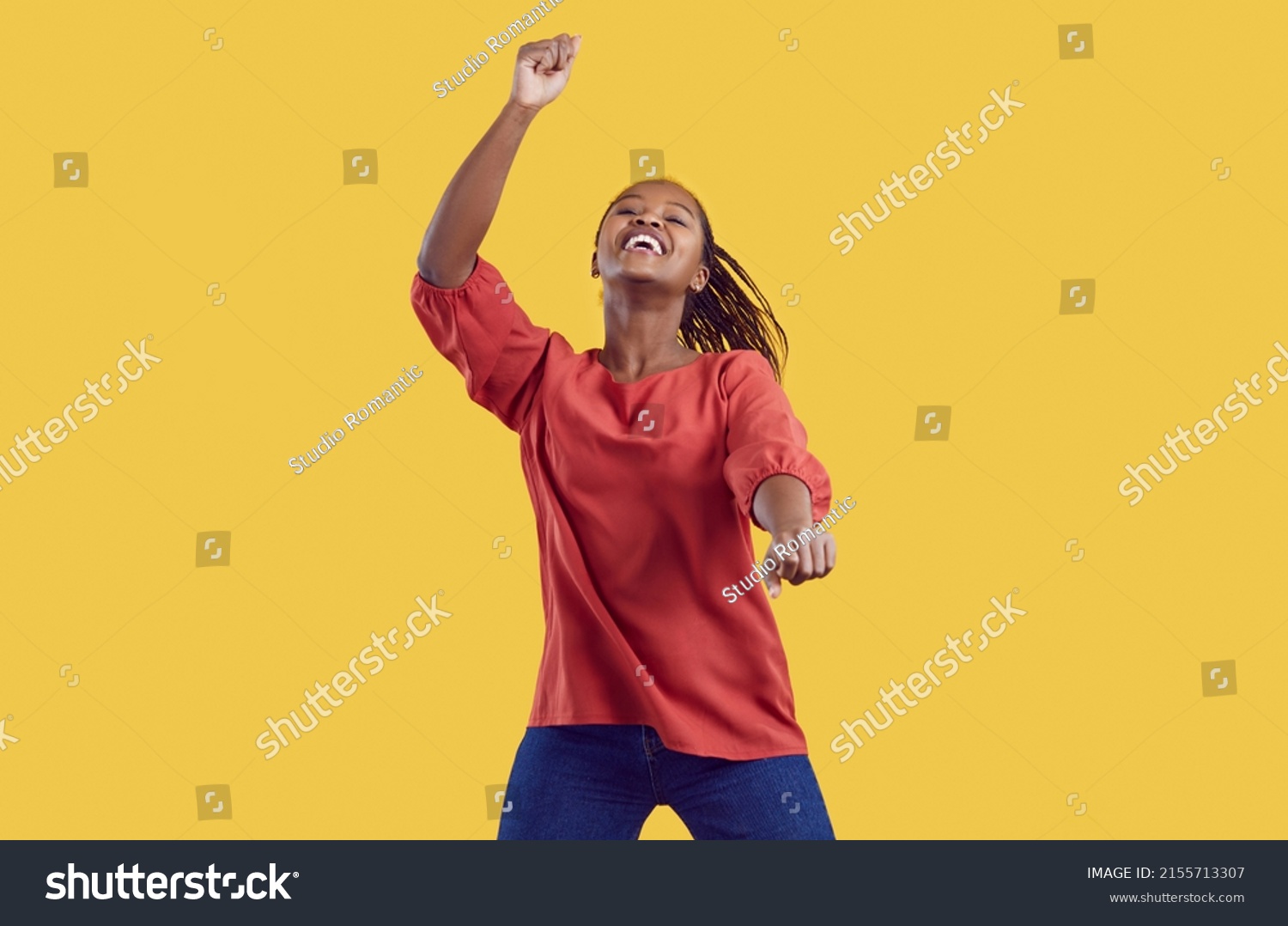 Excited millennial African American girl isolated on yellow studio background dancing listening to music. Smiling young black woman have fun make dancer moves Gangnam style. Entertainment. #2155713307