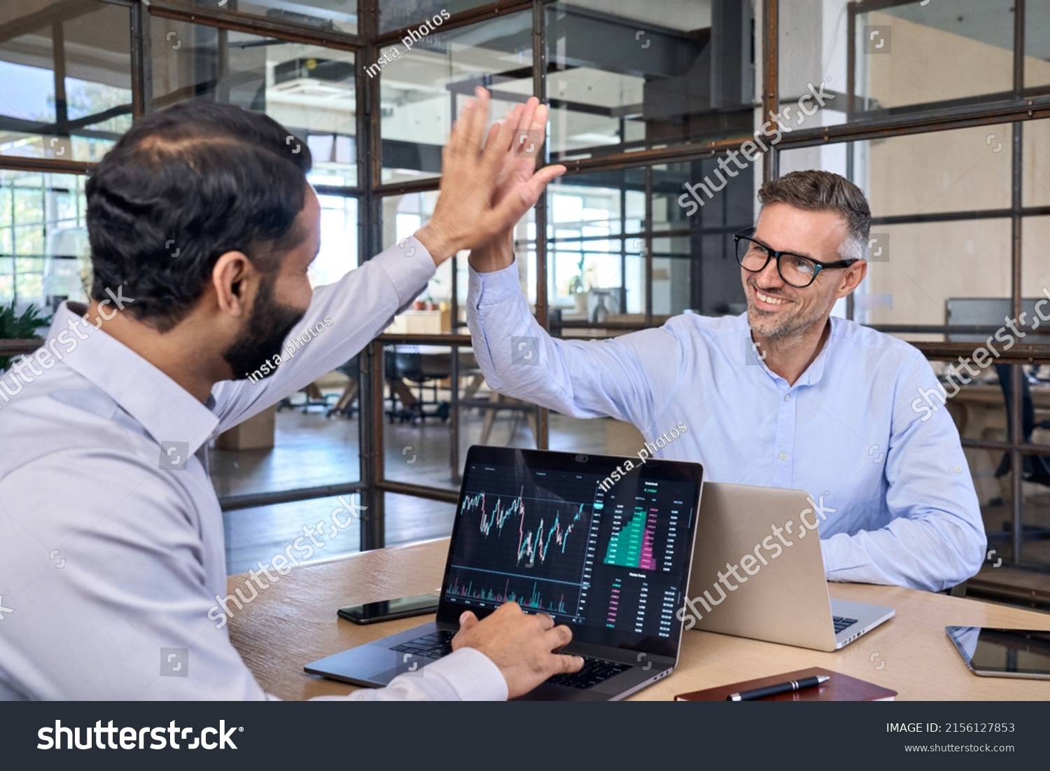 Two happy successful excited diverse traders investors giving high five celebrating successful stock exchange trading deal, rising crypto bull market shares growth, ipo profit victory concept. #2156127853
