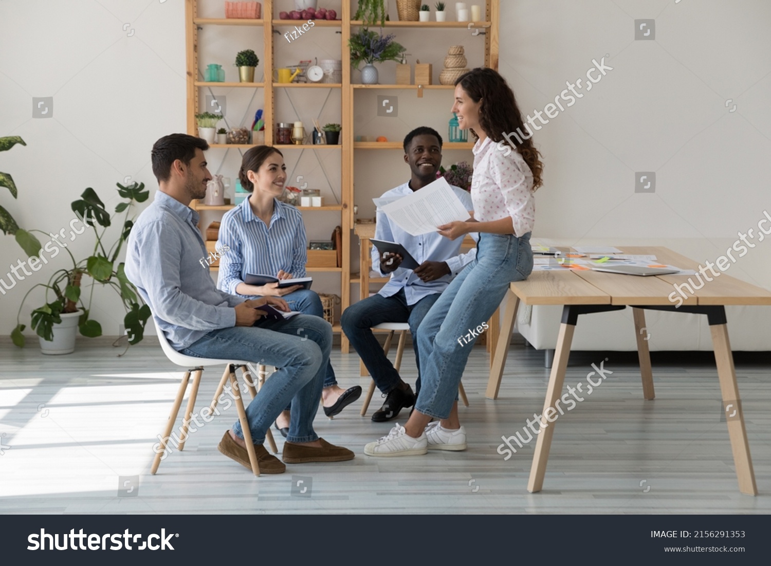 Female mentor and intern sitting, standing in circle on corporate training meeting, talking, laughing. Business project leader talking to employees, brainstorming, having fun #2156291353