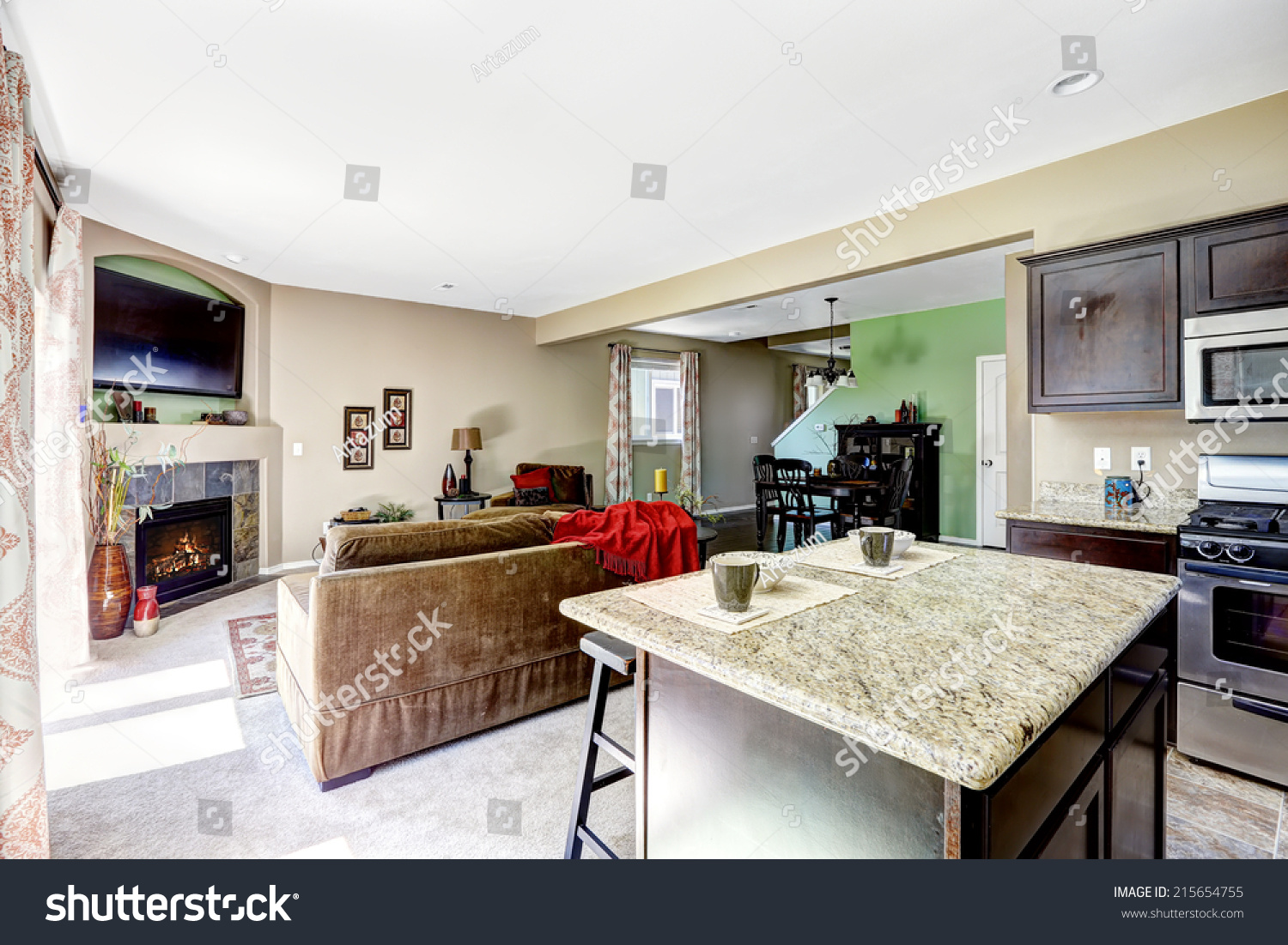 House interior with open floor plan. View of kitchen island with granite top and living room with fireplace #215654755