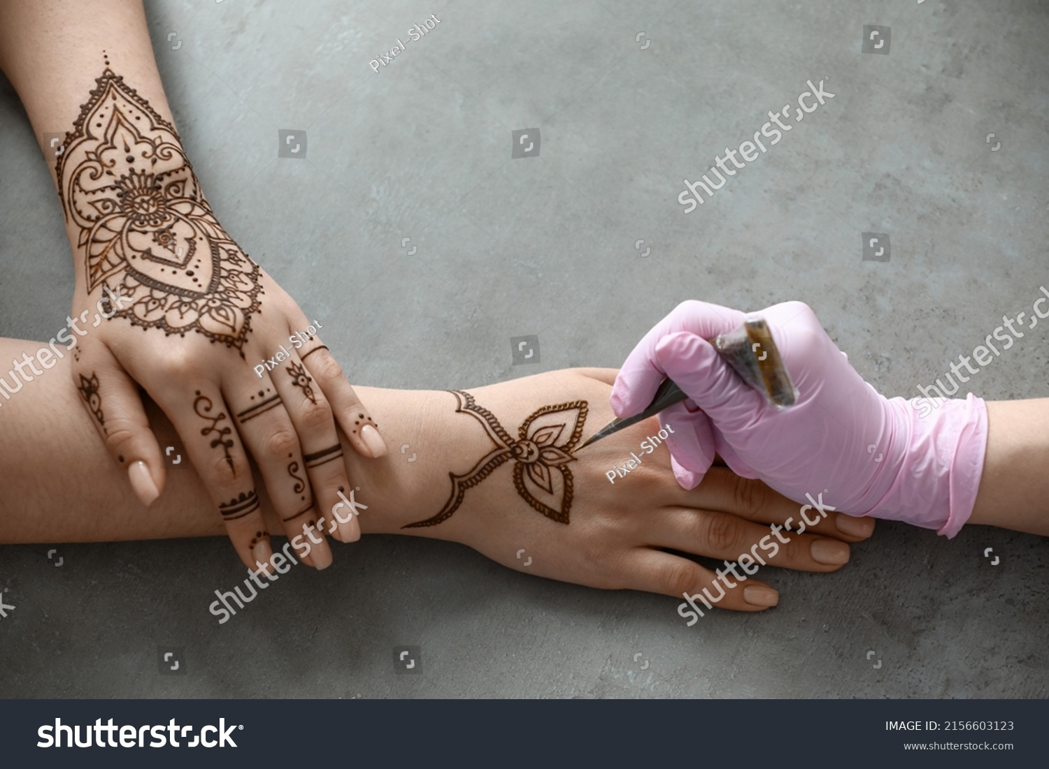 Mehndi master drawing henna tattoo on female hand in salon #2156603123
