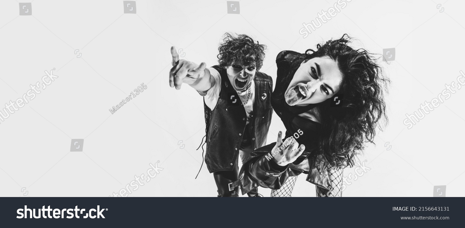 Timeless rock-and-roll. Black and white portrait of rock music fans, young boy and girl wearing black leather outfits moving on white studio background. Concept of style, art, fashion and youth, ad #2156643131