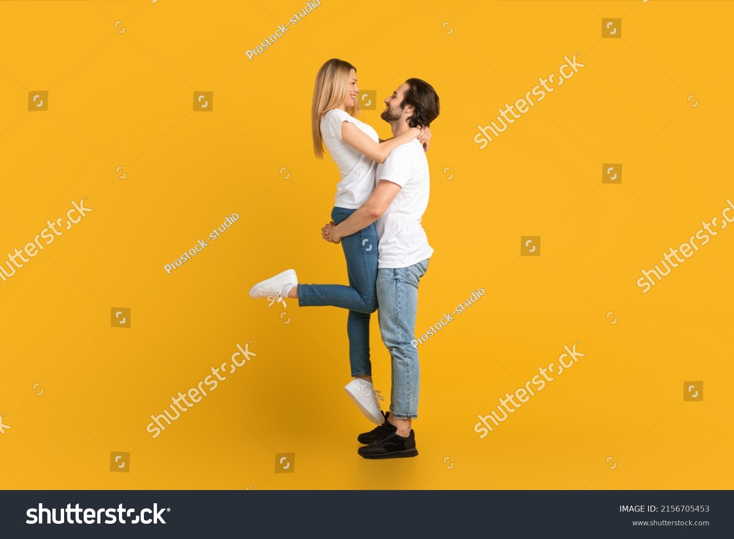 Cheerful young european male with beard raises female, isolated on yellow background, studio, full length, profile. Relationship, love, romance, advertising and offer, win and huge sale, copy space #2156705453