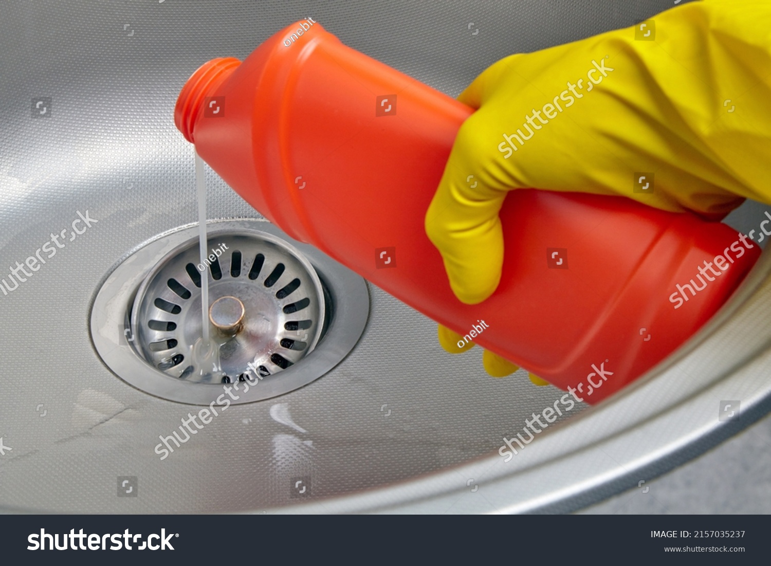 Hand in yellow rubber glove pour sewer pipe cleaner down the kitchen sink drain. Kitchen and drain cleaning work #2157035237