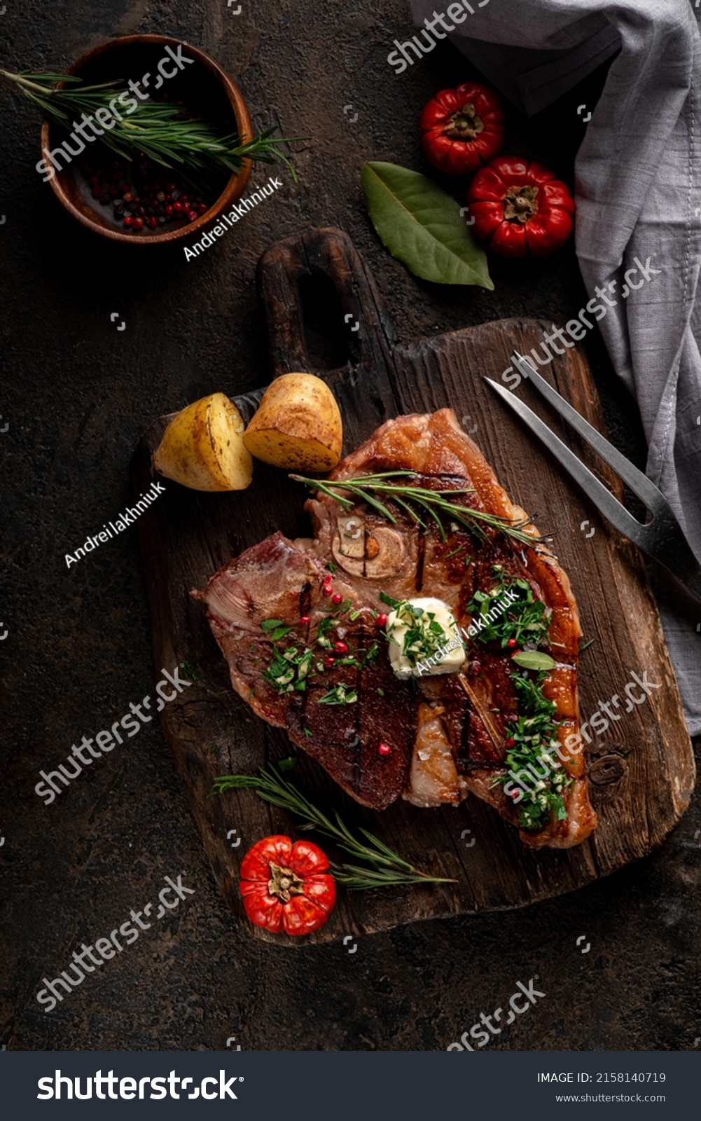 Porterhouse roast steak or Florentine beef steak with butter on a cutting board with seasonings and vegetables. Dark rustic wooden background. View from above. #2158140719