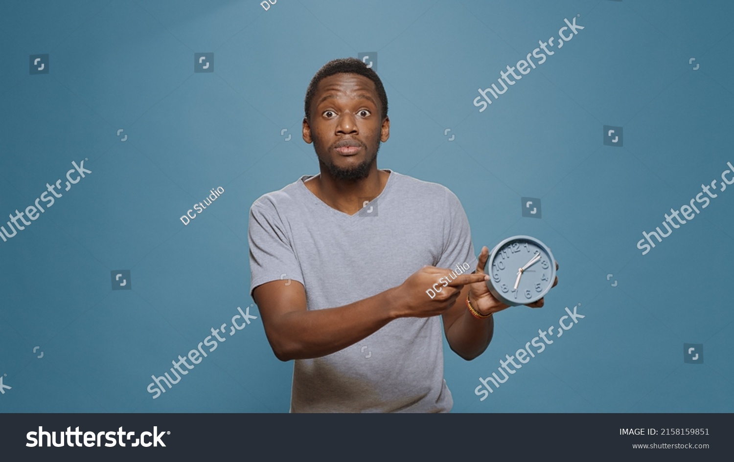 Stressed man checking time on wall clock and running late to work, looking at hour and minutes. Young adult in delay, doing alarm countdown to measure time, being impatient and punctual. #2158159851