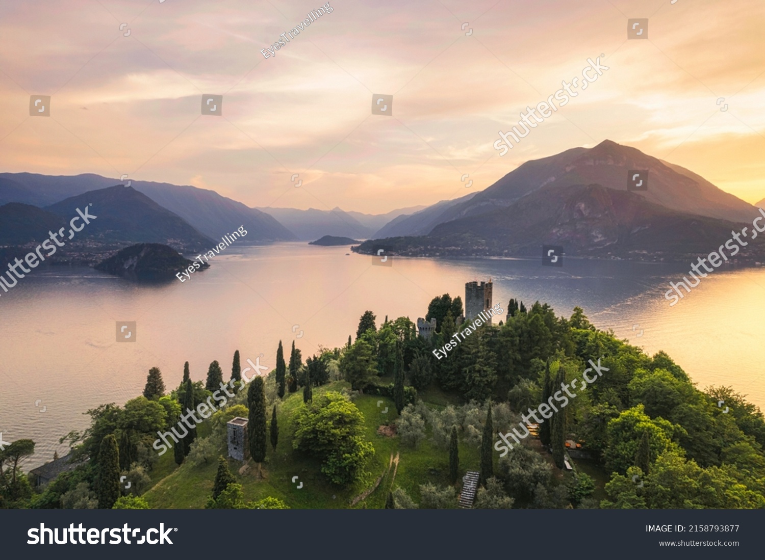Vertical panoramic aerial view of Vezio Castle with Varenna village and mountains in background during summer sunset. Drone shot in Como lake. Varenna, Italy #2158793877