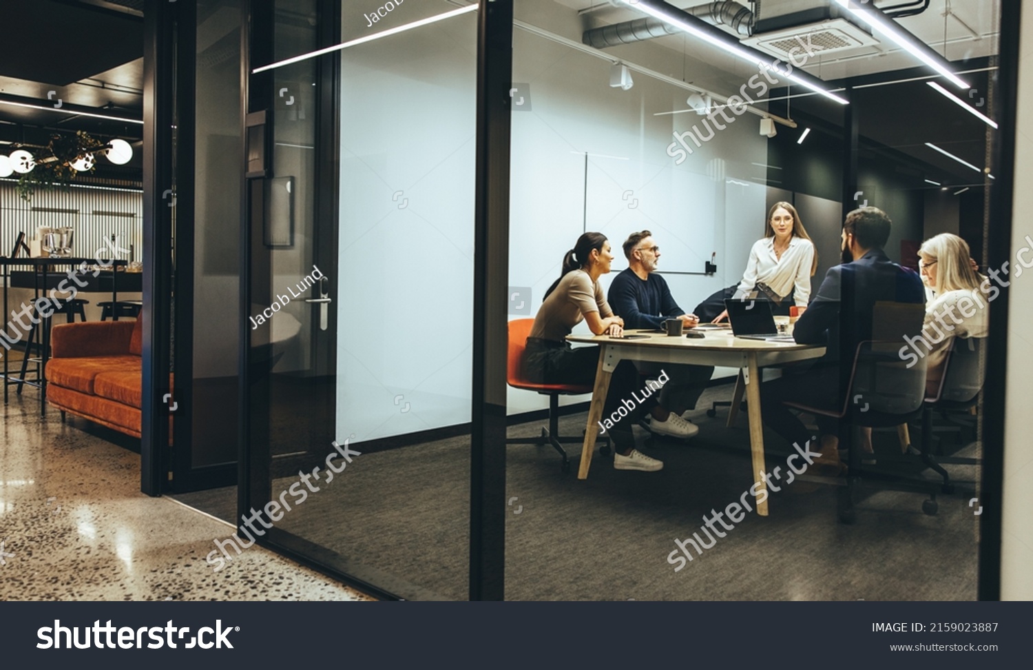 Team of diverse businesspeople having a meeting in a transparent boardroom. Group of business professionals having a discussion during a briefing. Colleagues collaborating on a new project. #2159023887