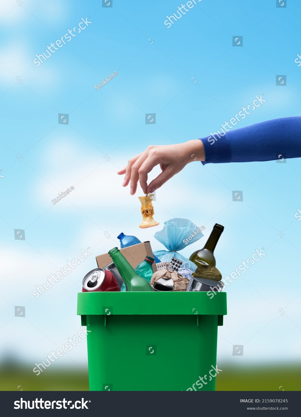 Woman putting food leftovers in a undifferentiated waste bin, improper waste management concept #2159078245