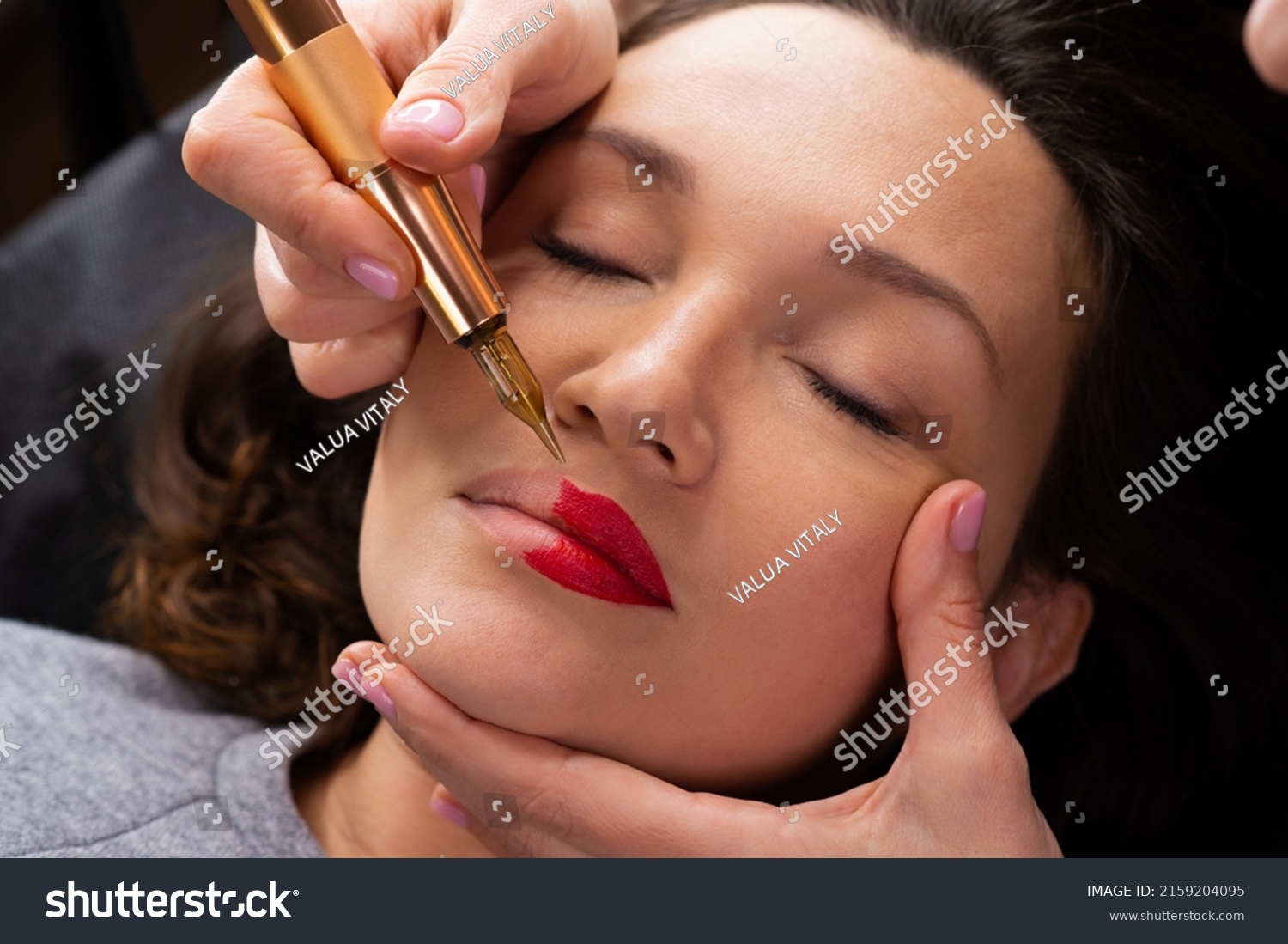 Young woman making lips tatouage in a dressing makeup room. Lips tatouage process .Woman making lips blushing. Make-up artist in beauty studio doing makeup for beautiful girl. Making mua. #2159204095
